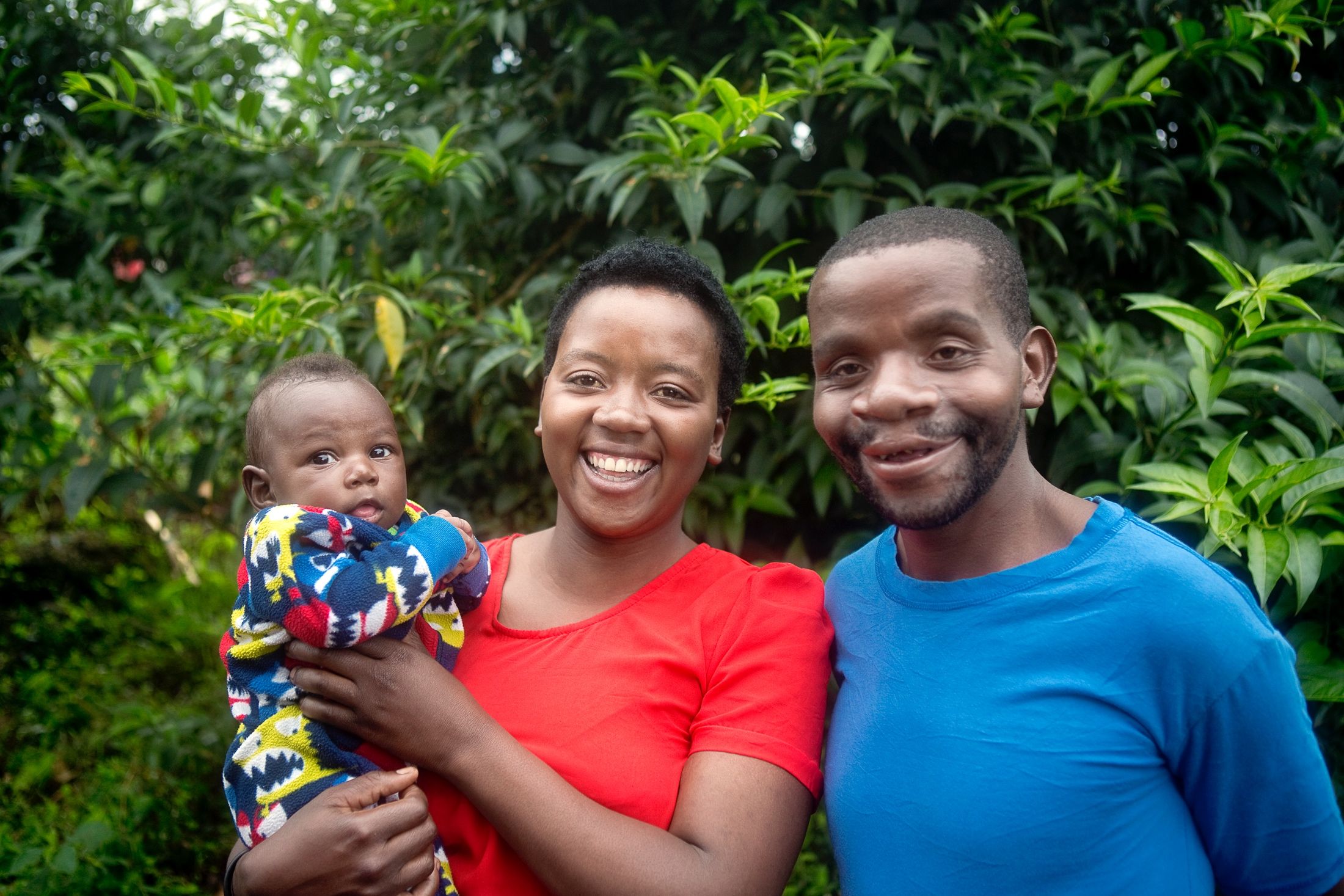 Enok tillsammans med sin fru och deras barn, alla ler mot kameran och frun håller barnet i famnen.