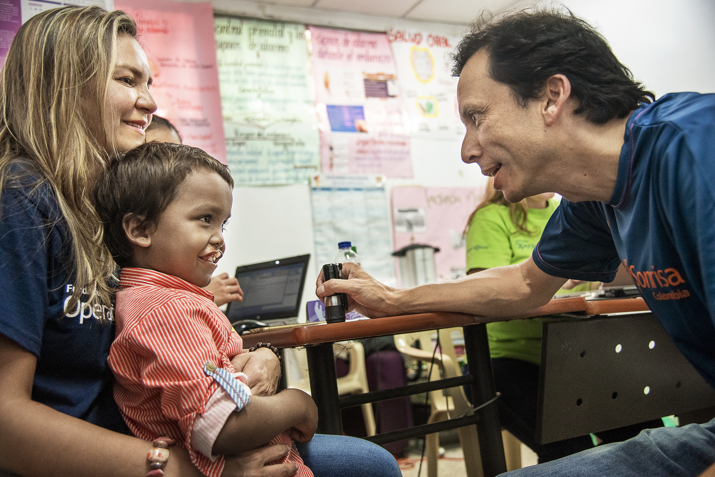 En manlig läkare talar med och undersöker en 7-årig pojke med läpp-käk-gomspalt. Pojken sitter i knät på en kvinna.