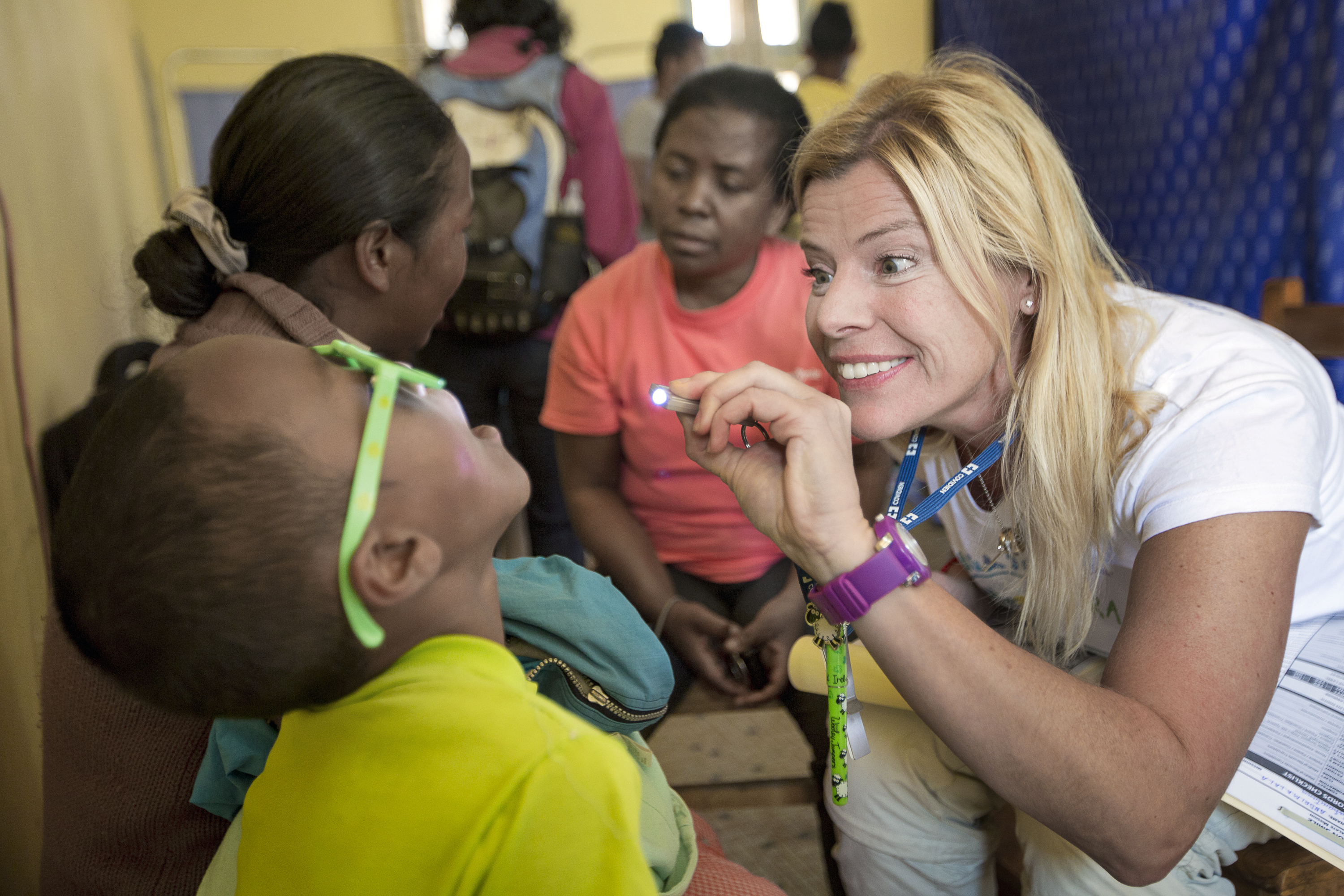Plastikkirurgen Petra Peterson lyser in i ett barns mun under den obligatoriska hälsoundersökningen.