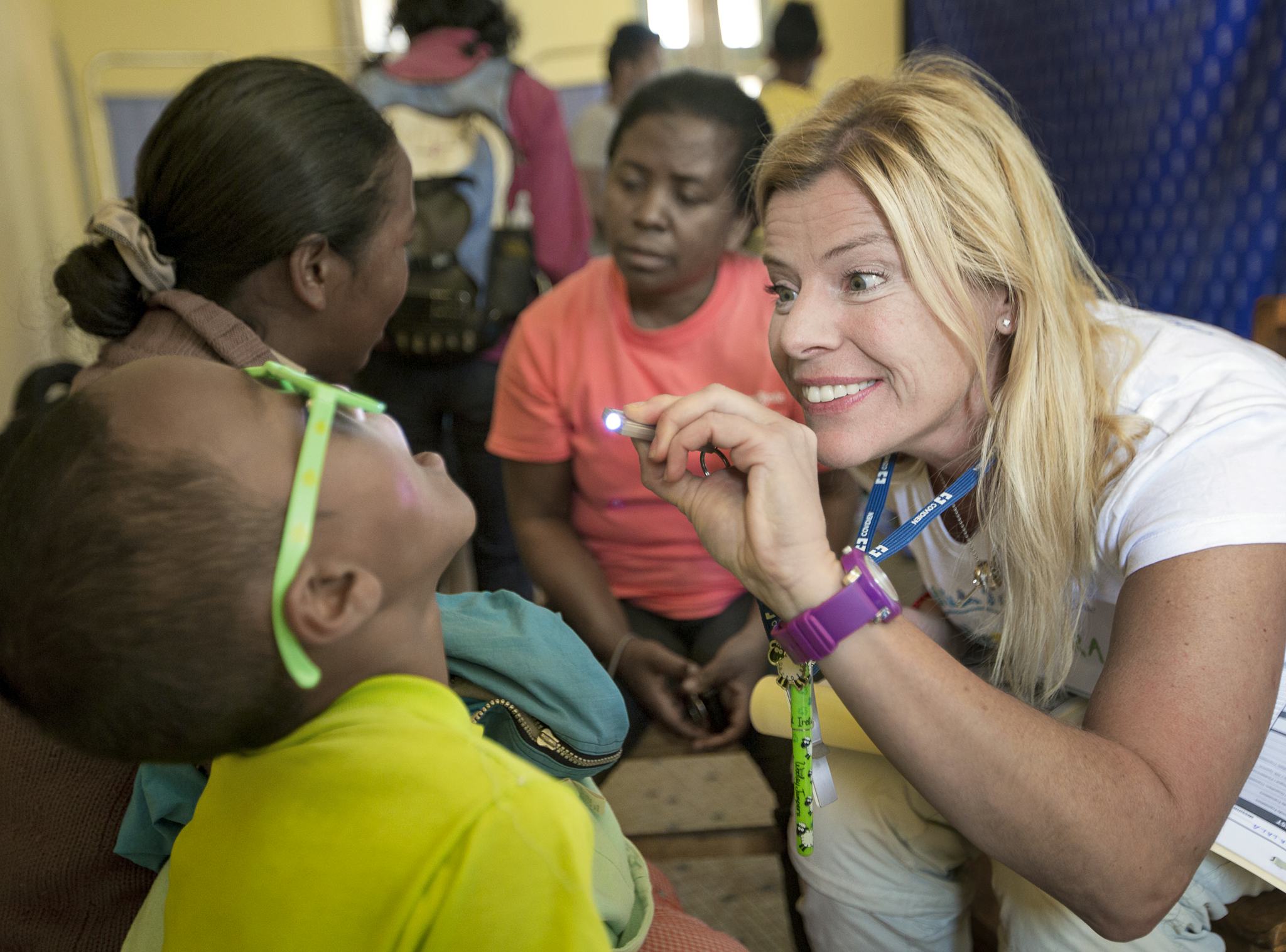 Plastikkirurgen Petra Peterson lyser in i ett barns mun under den obligatoriska hälsoundersökningen.