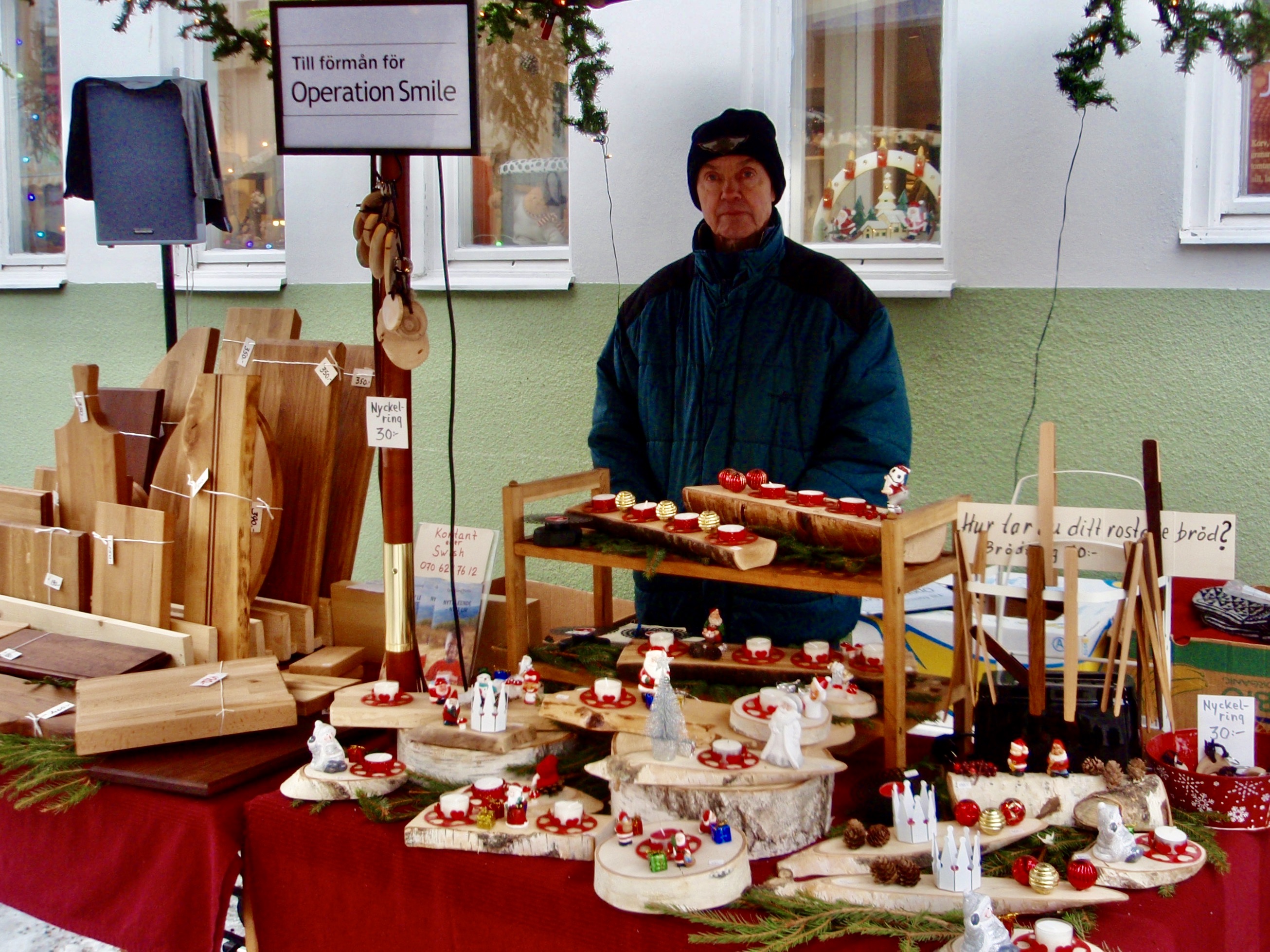 En man står vid ett bord fyllt av juliga hantverk