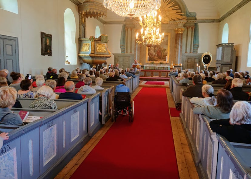 Kyrka med människor som sitter på kyrkbänkar