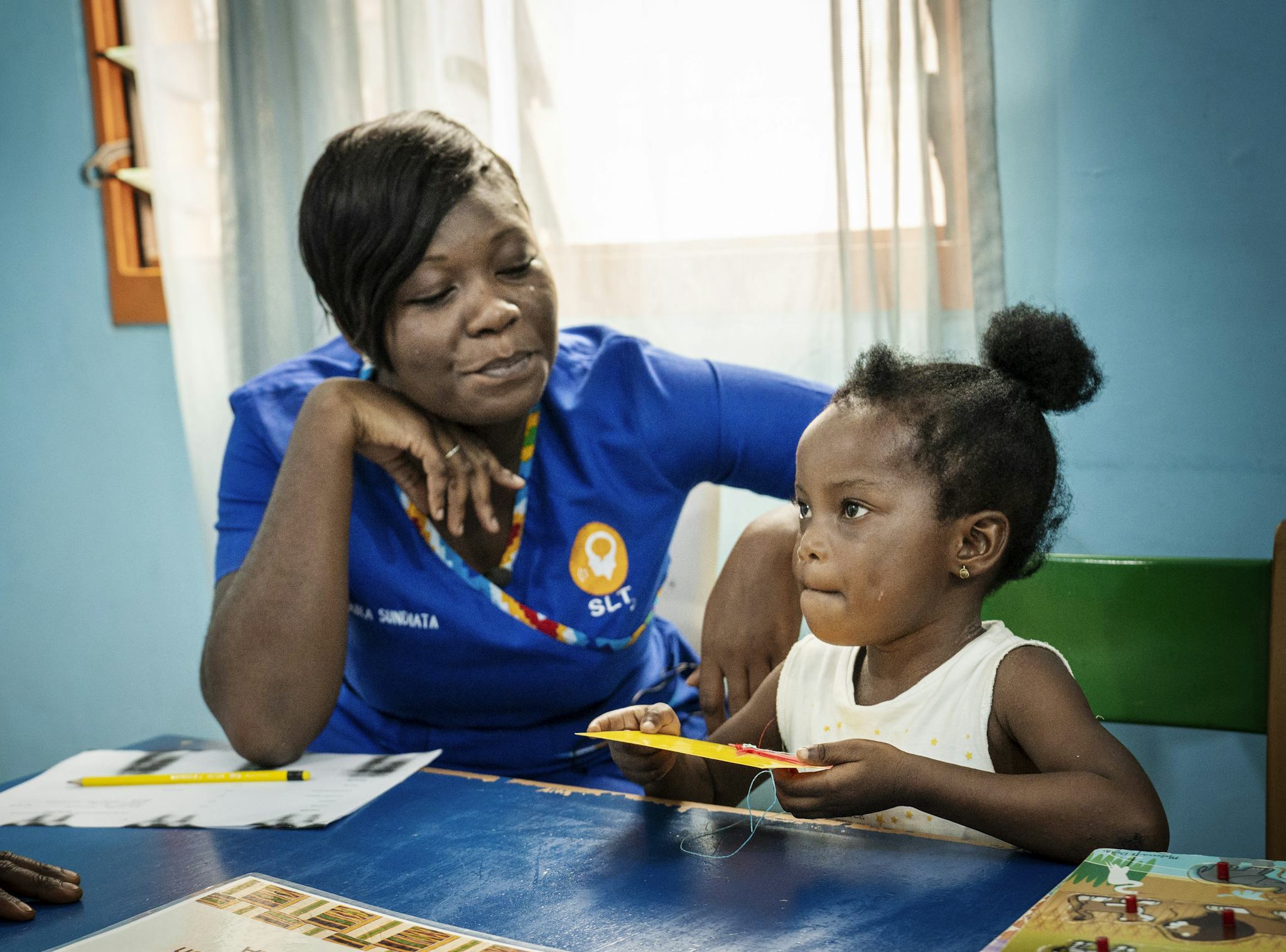 En kvinnlig logoped tränar tillsammans med en treårig flicka för att förbättra patientes tal.