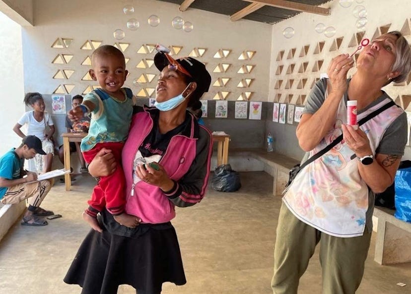 Anna blåser såpbubblor mot ett barn och hens förälder