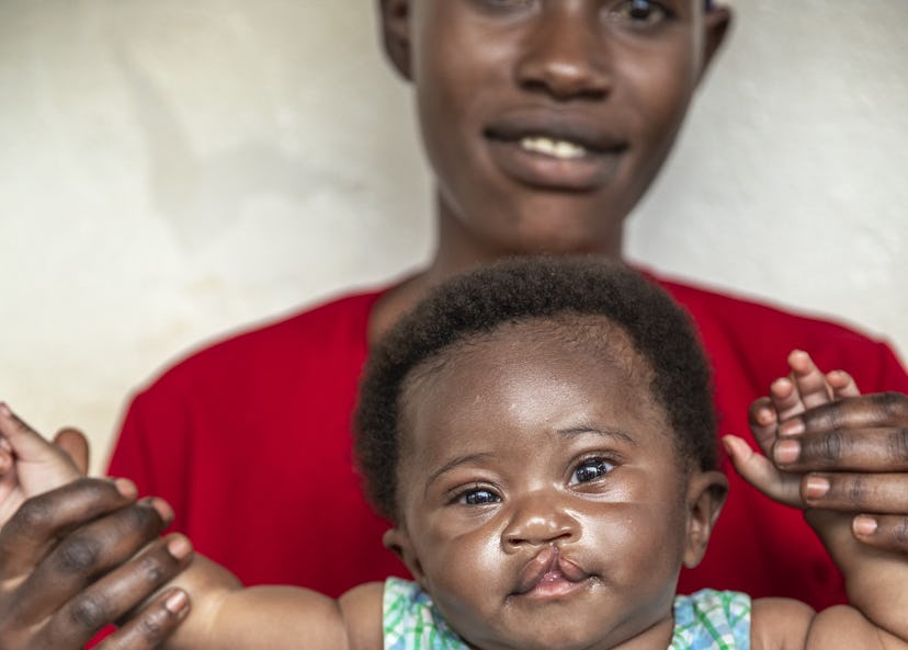 Kenny sitter i sin mammas knä och tittar in i kameran