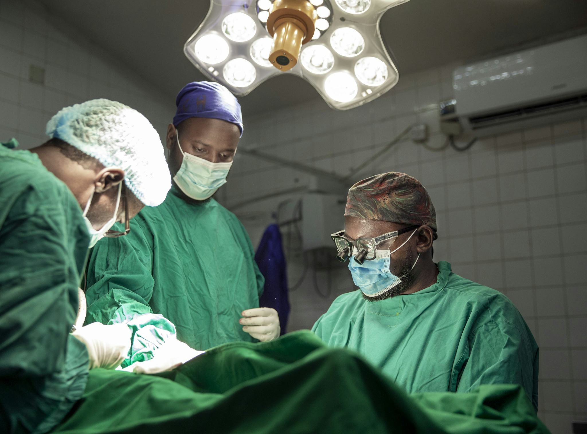 Tre kirurger arbetar med en patient i operationssalen