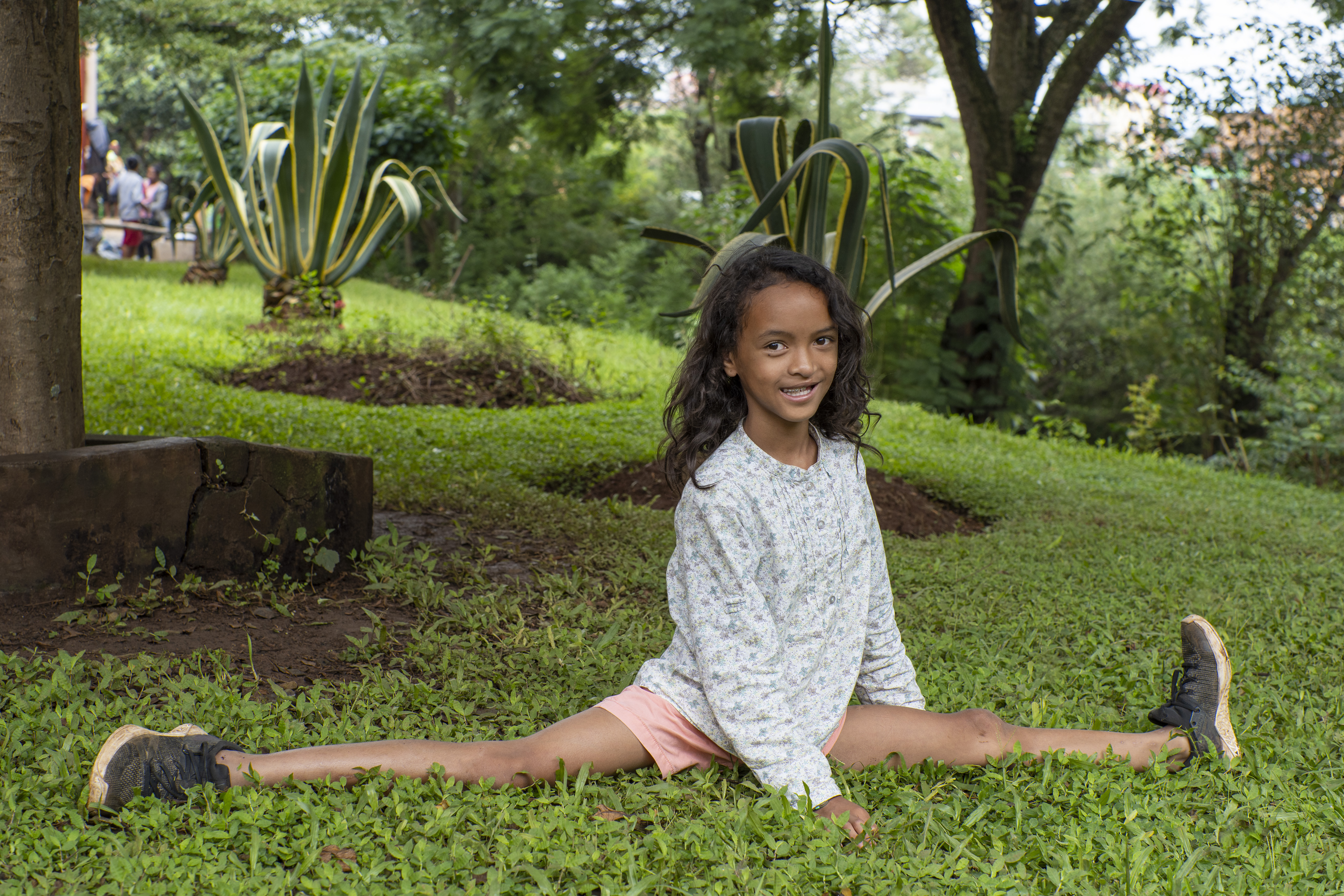 Joyce tittar leende in i kameran. Hon sitter i spagat.