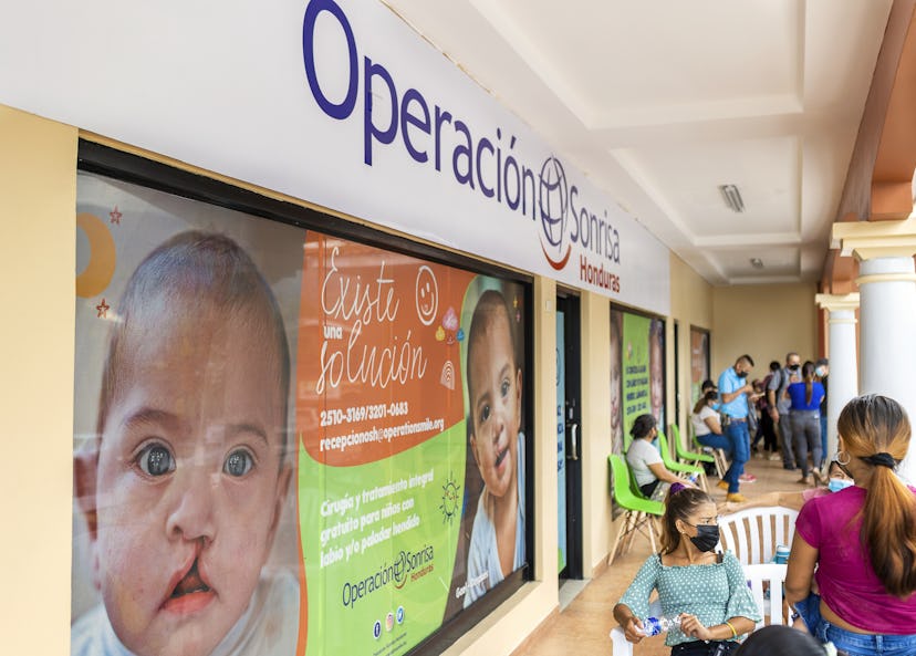Människor sitter på plaststolar utanför entrén till Operation Smiles klinik.