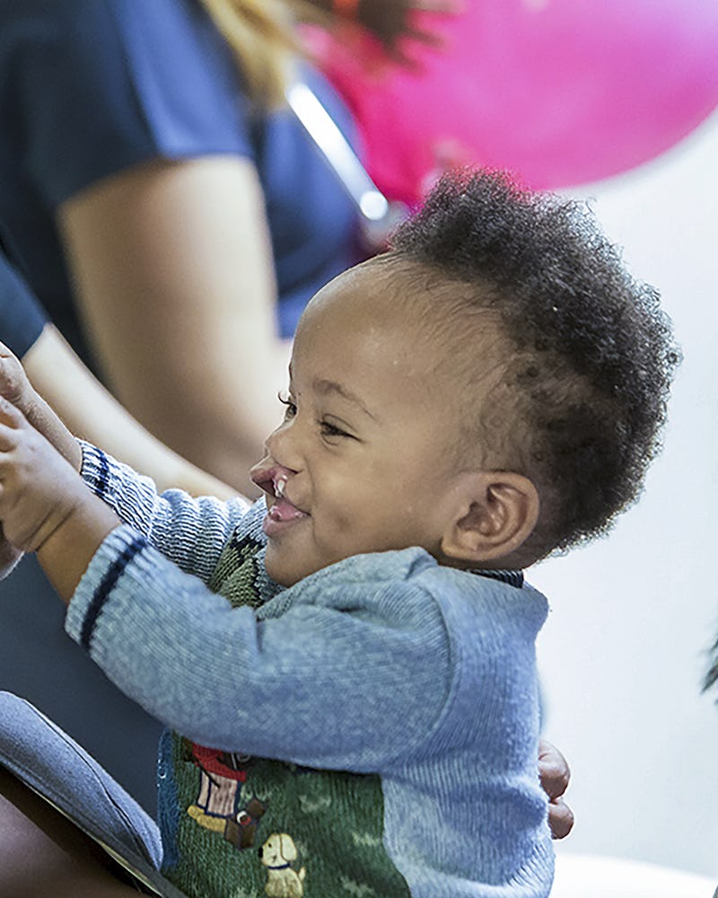 En pojke med läppspalt busar med sin mamma och lägger en id-bricka mot hennes näsa.