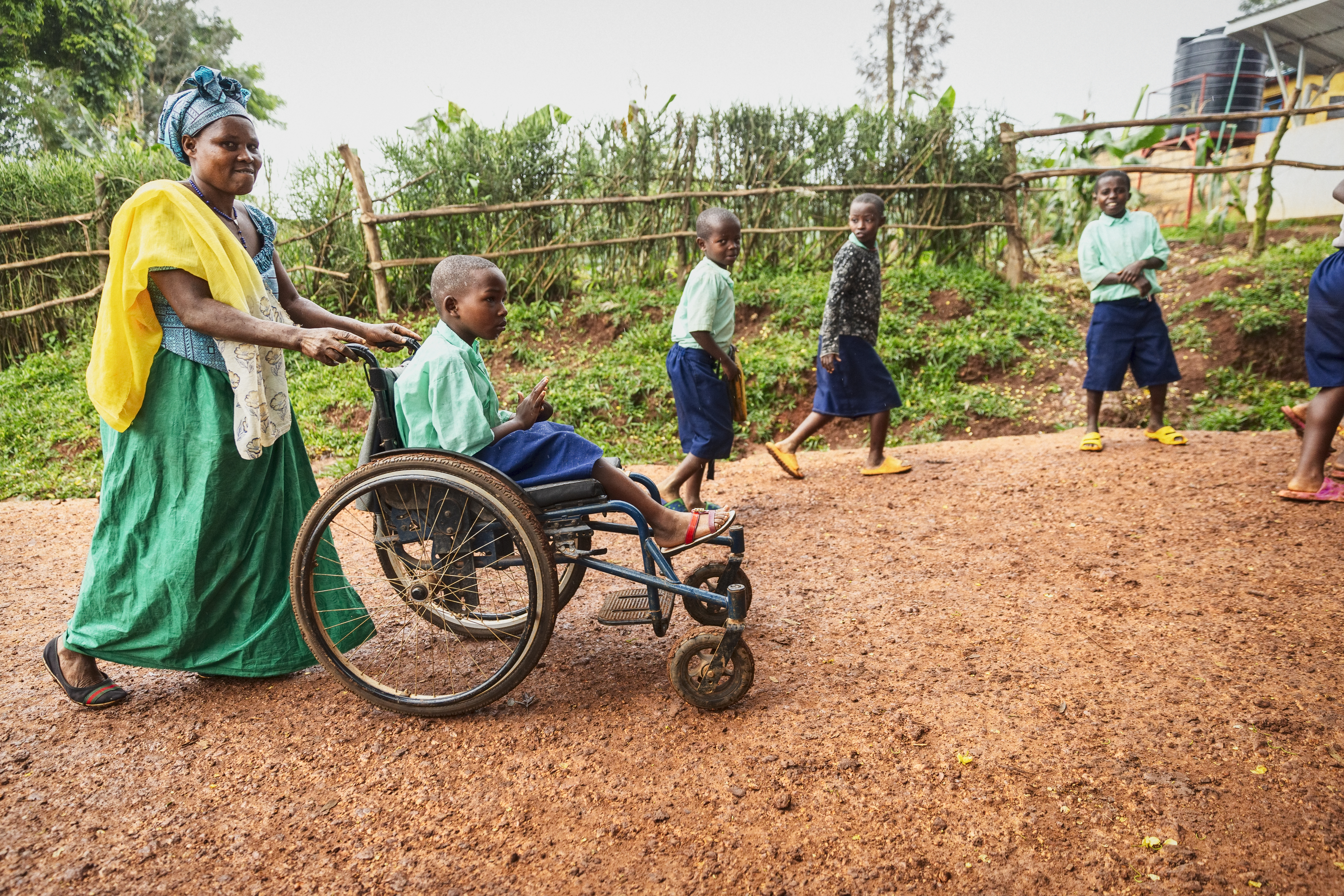 Sylvie med brännskadat ben och arm blir körd i rullstol av hennes gudmor Francine
