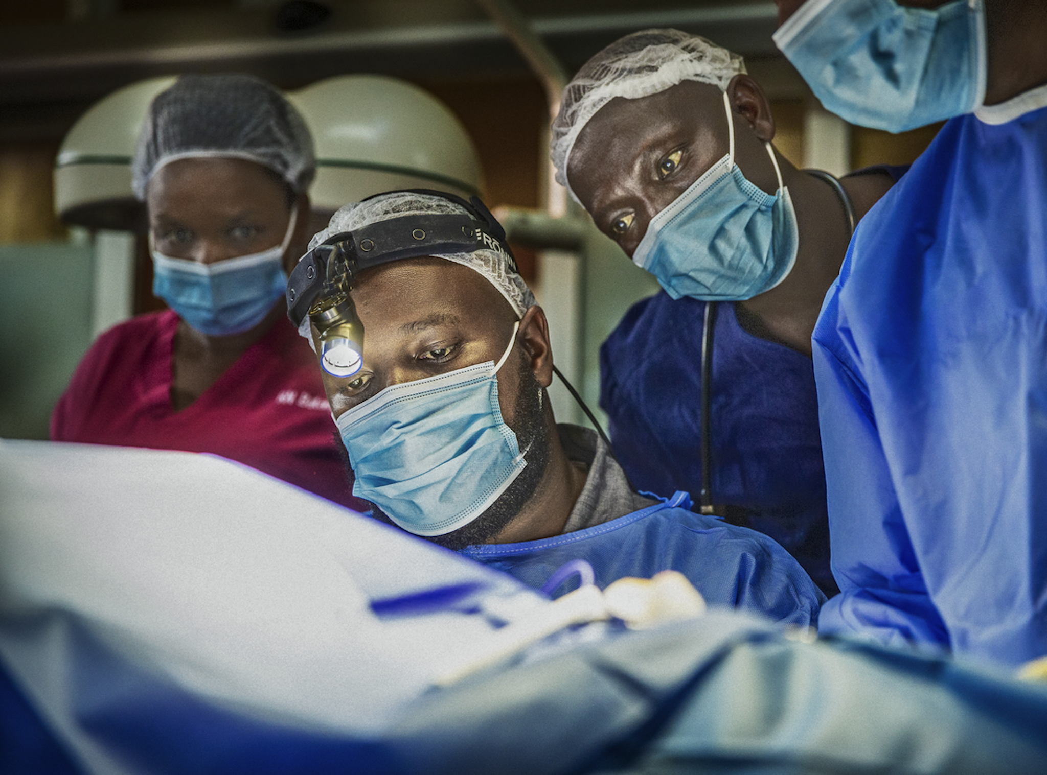 Dr Clovis Baramburiye vid ett operationsbord med medarbetare runt sig.