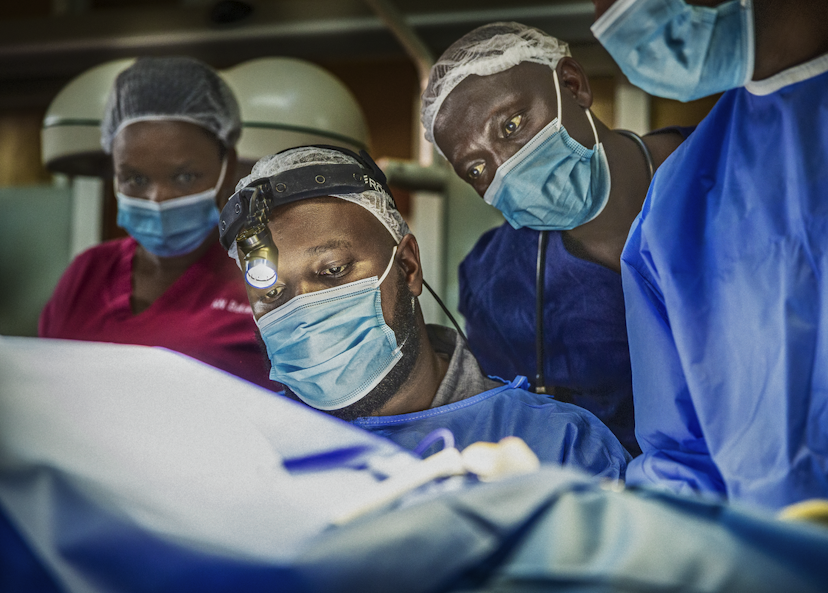 Dr Clovis Baramburiye vid ett operationsbord med medarbetare runt sig.