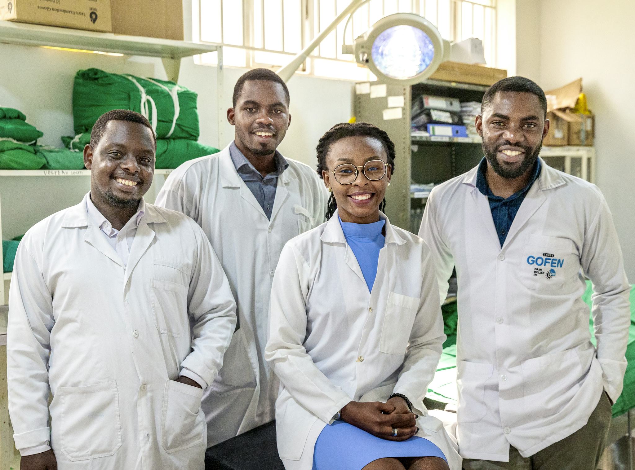 tre manliga och en kvinnlig kirurg i vita rockar, tittar in i kameran