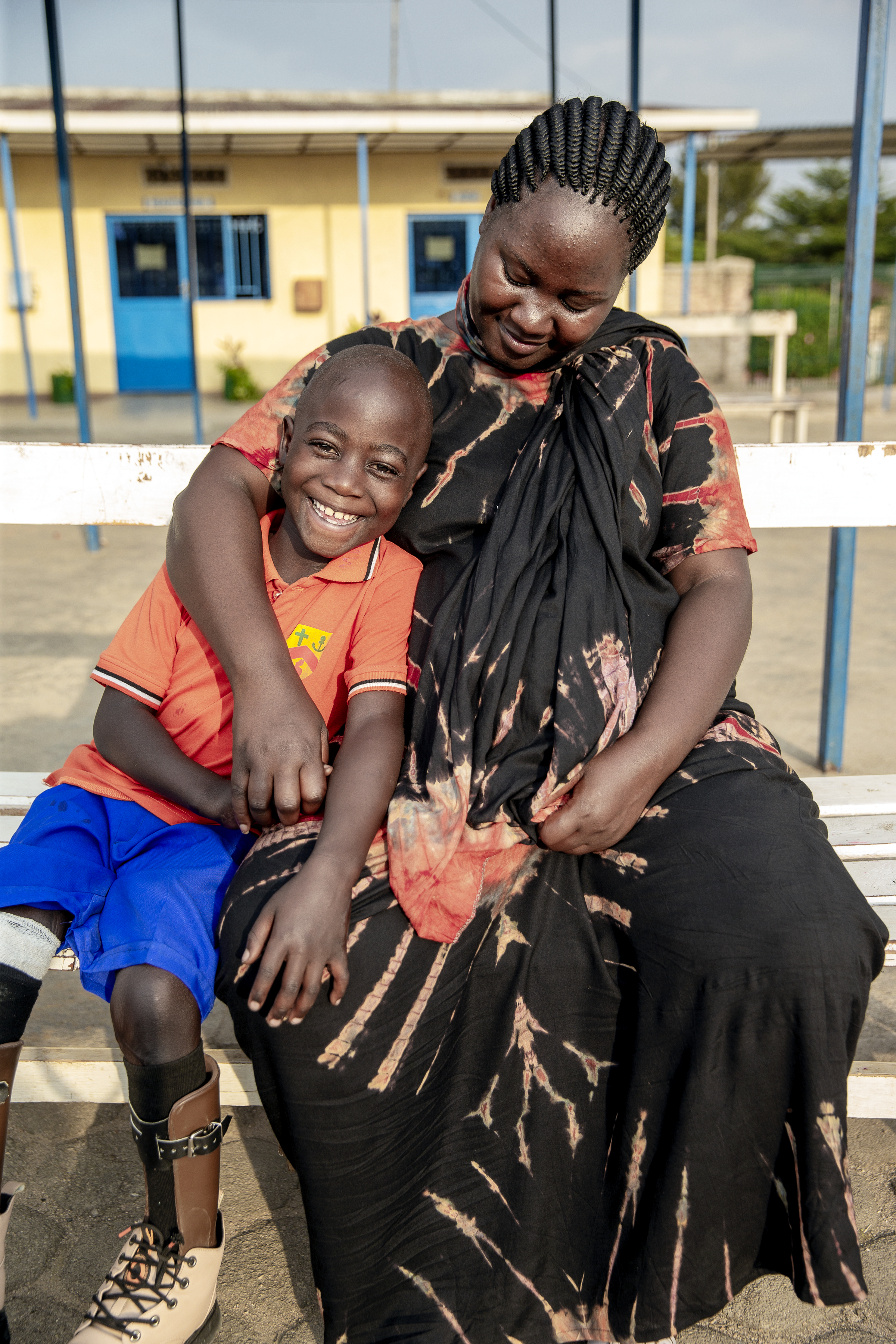 Chris Joy sitter tätt intill sin mamma. De ser mycket glada ut och Chris Joy har sina nya proteser på sig.