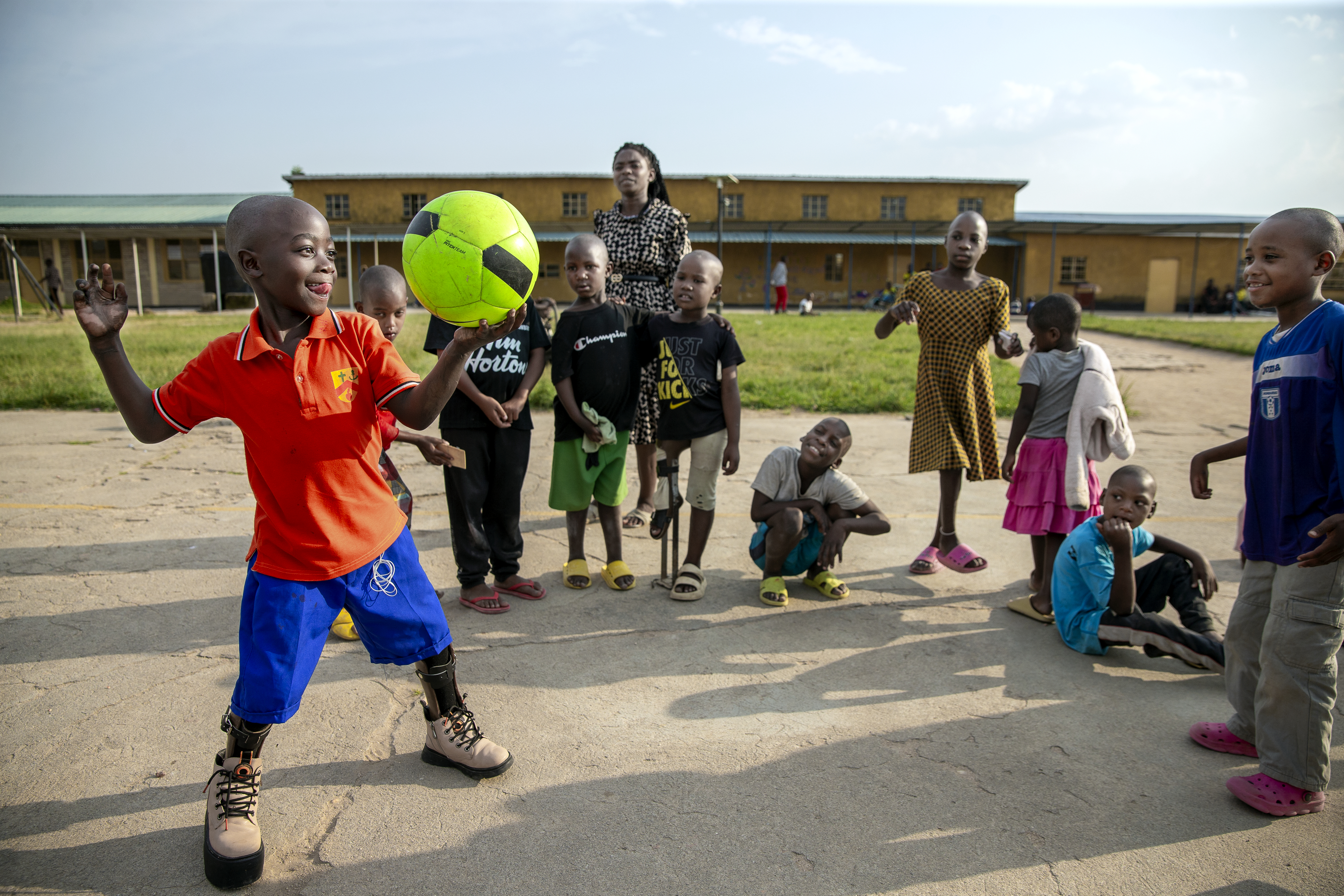 Flera barn utomhus som leker med en grön fotboll.