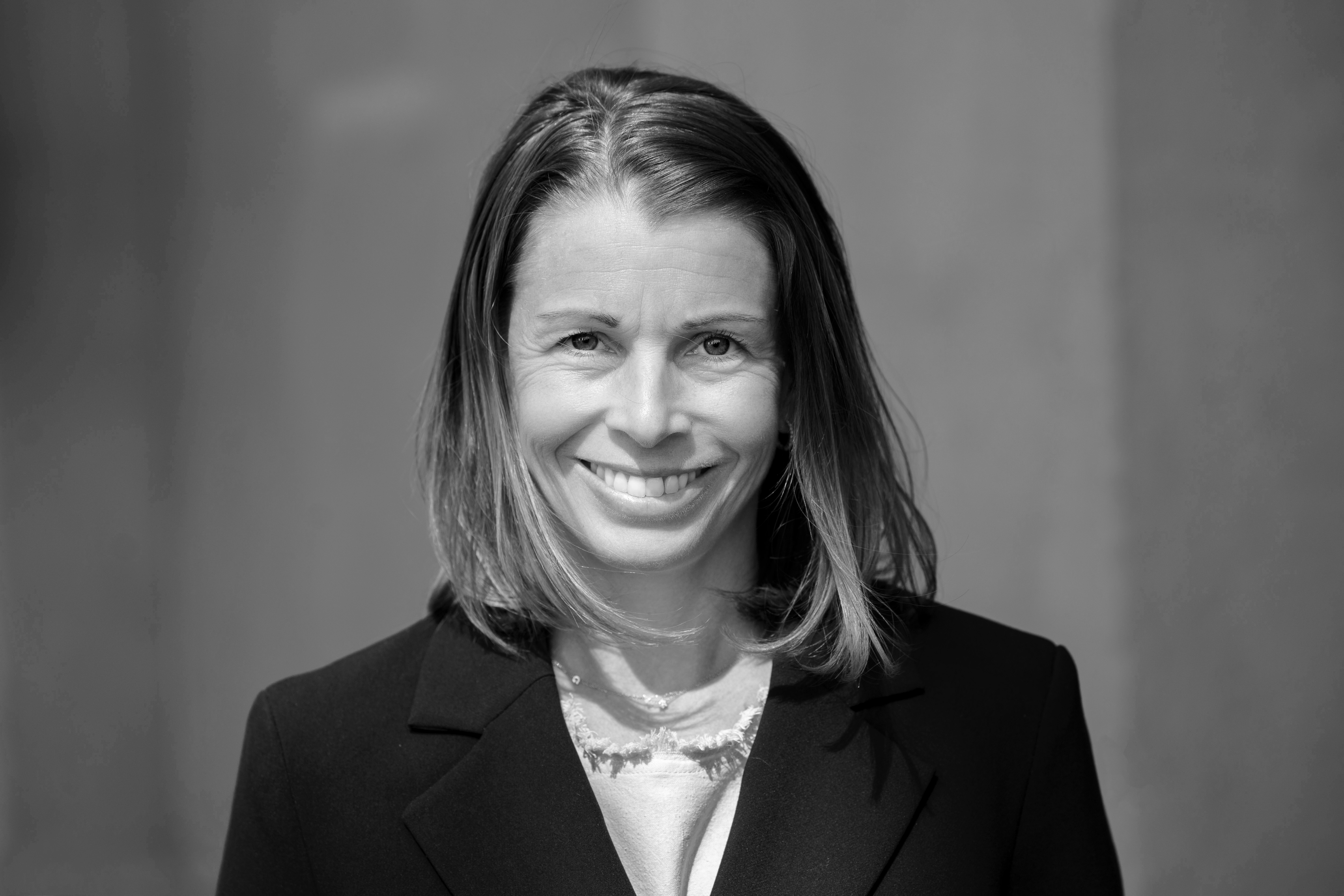 Svartvit bild på kvinna som ser in i kameran och ler.