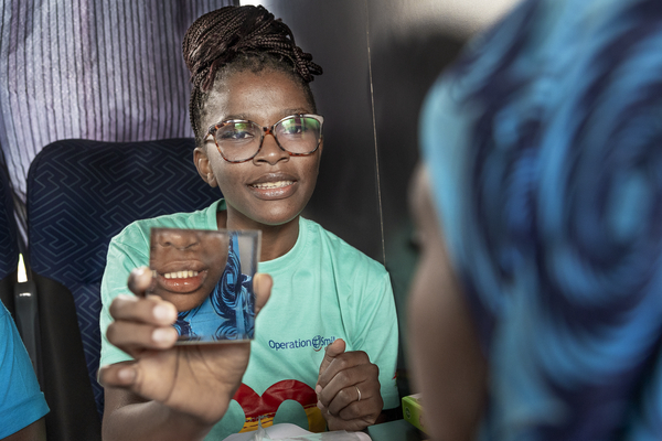 En logoped håller upp en spegel mot en patient som taltränar