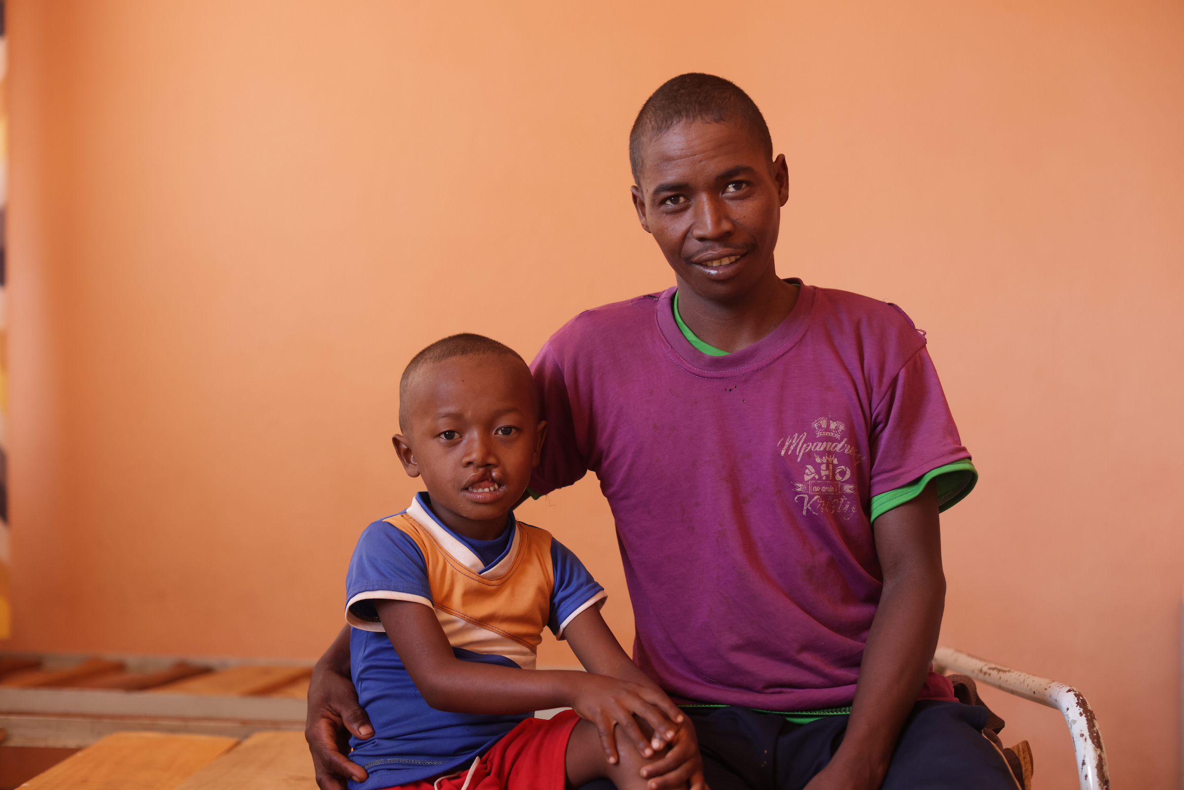 En liten pojke som heter Najasina sitter bredvid sin pappa i ett kalt rum i väntan på att bli undersökt inför en potentiell operation för sin läppspalt.