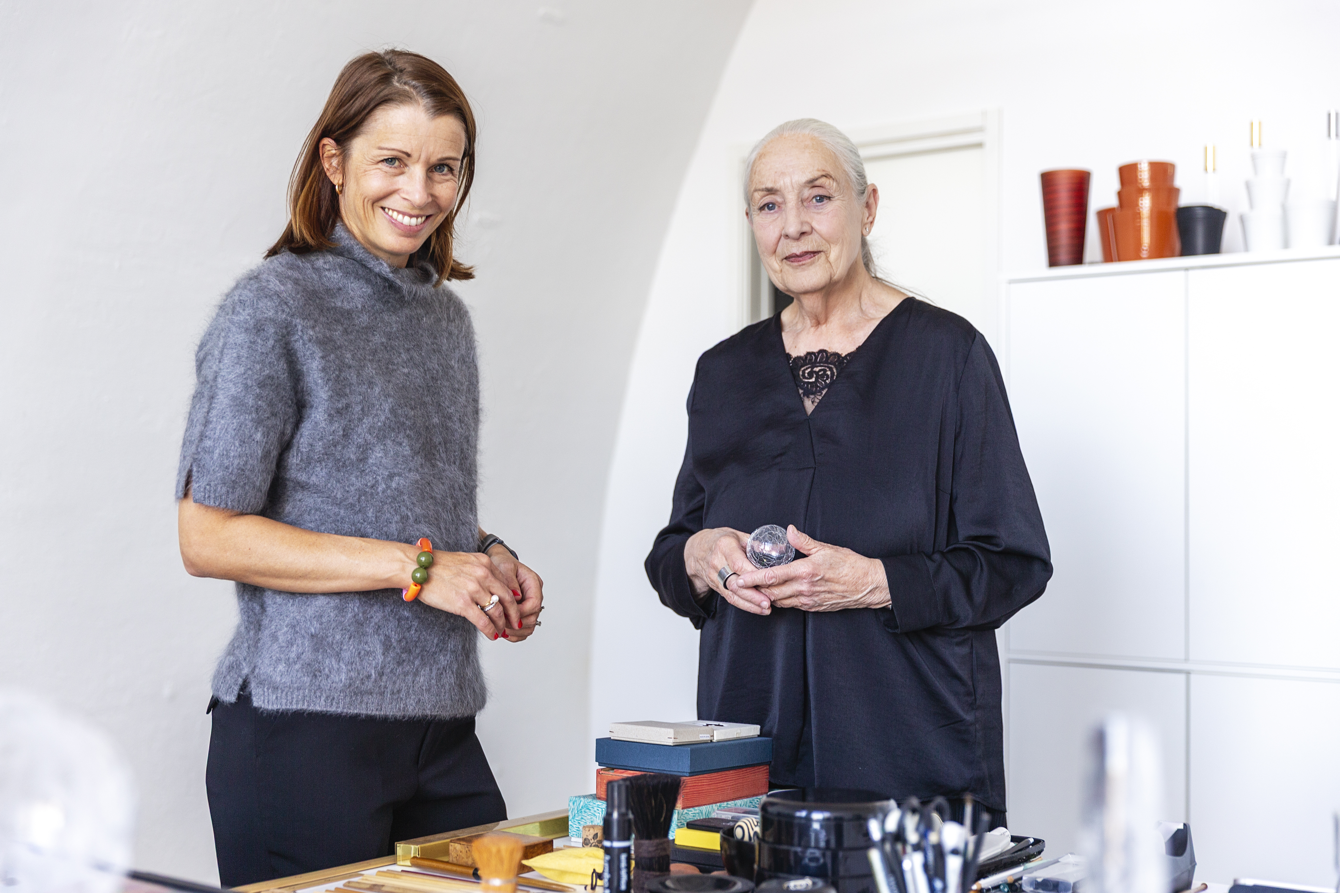 Formgivare Ingegerd Råman tillsammans med Operation Smiles generalsekreterare Malin Söderström framför ett bord med konstverk.