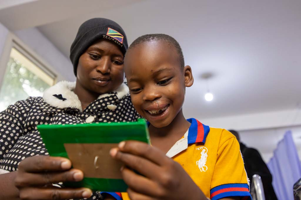 En kvinna och ett barn tittar tillsammans på en grönramad surfplatta eller enhet inomhus.